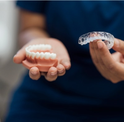 A Person Holding A Clear Dental Aligner And A Teeth Model In The Other at Charleston West Virginia